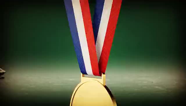 Złoty medal na wstędze unosi się i obraca, w tle przemyka bobslej